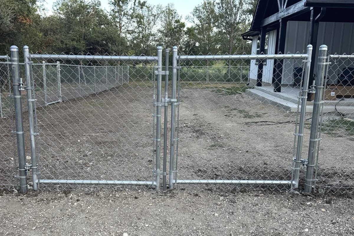 New galvanized chain link fence with a double drive gate around a residential yard