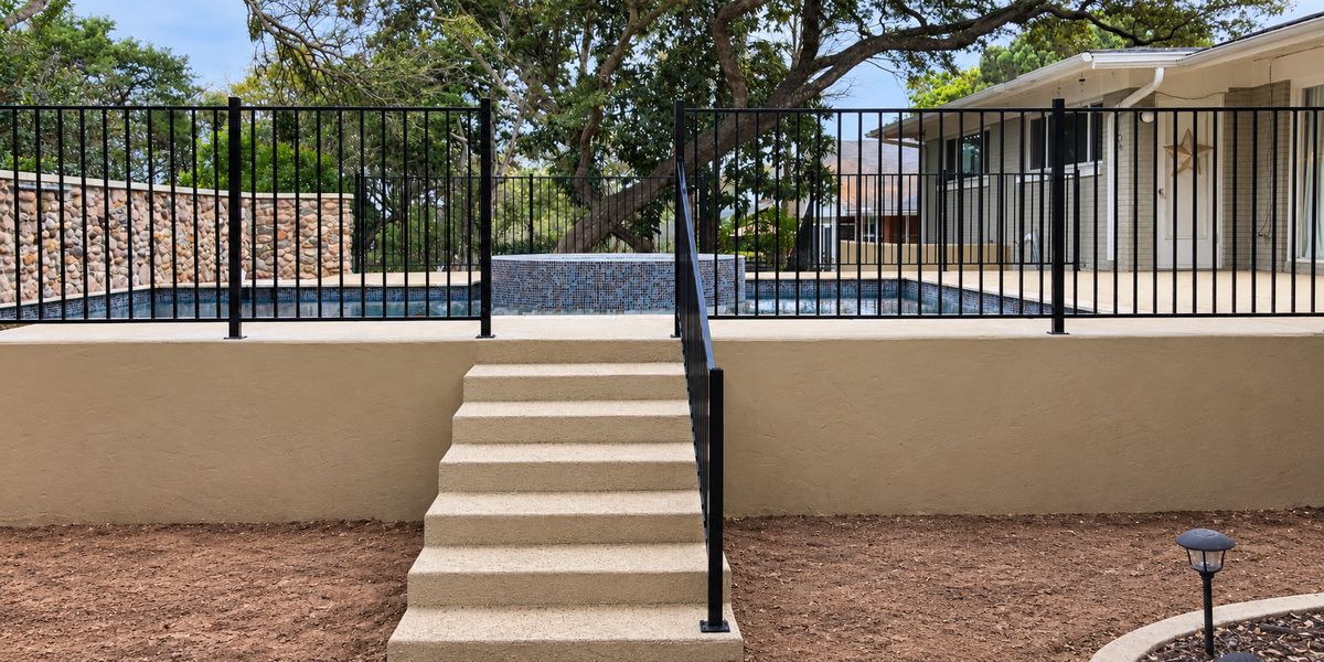 Black ornamental iron pool fence with matching handrail on a backyard staircase